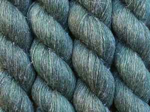 A close up of semi-solid deep green with hints of charcoal, emerald, chartreuse and kelly green coloured skeins of non-superwash baby alpaca, silk and linen 4ply fingering weight yarn (Nori on Spinifex)